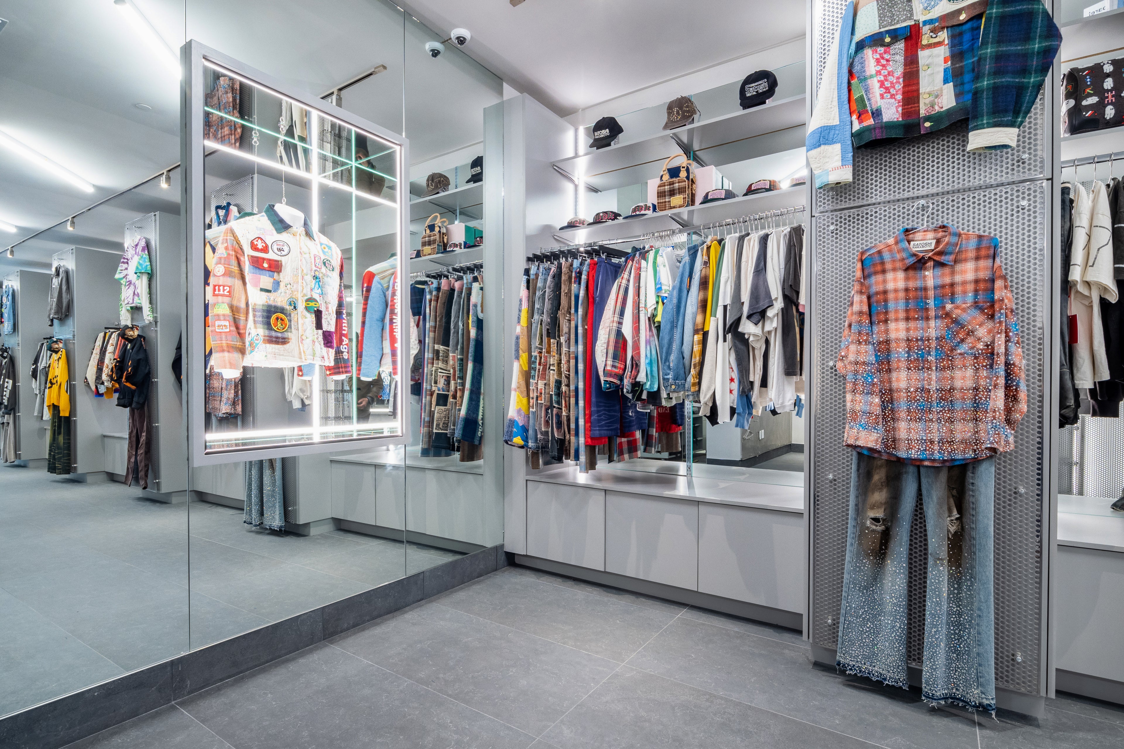 Clothing store interior with racks and mirrors displaying various outfits.